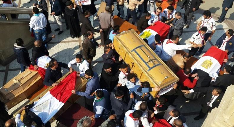 Egyptian clergymen and officials carry the coffins of the victims of a church bombing in Cairo, on December 12, 2016