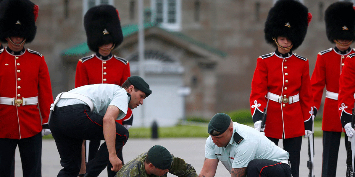 A member of the guard of honor is attended by colleagues after fainting before Mexican President Enrique Peña Nieto's inspection at the Citadelle in Quebec City, Canada.