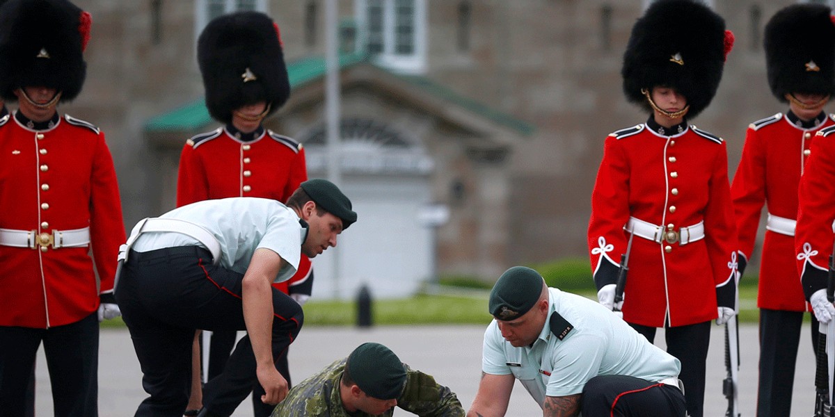 A member of the guard of honor is attended by colleagues after fainting before Mexican President Enrique Peña Nieto's inspection at the Citadelle in Quebec City, Canada.