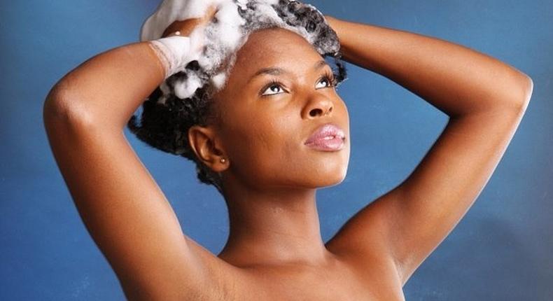 African American woman in towel shampooing her hair