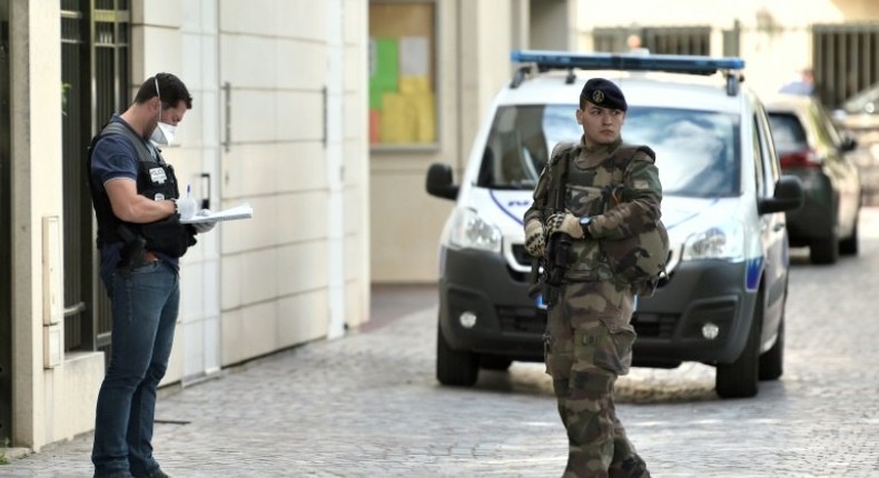 An armed French soldier patrols next to a forensic police officer near the site where a car slammed into soldiers in Levallois-Perret, outside Paris, on August 9, 2017