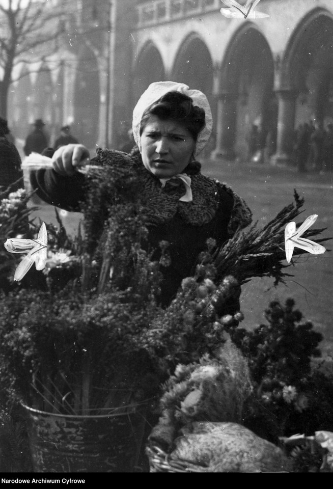 Sprzedaż palm wielkanocnych na Rynku Głównym w Krakowie. Kobieta kupuje palmę wielkanocną na straganie przed Sukiennicami