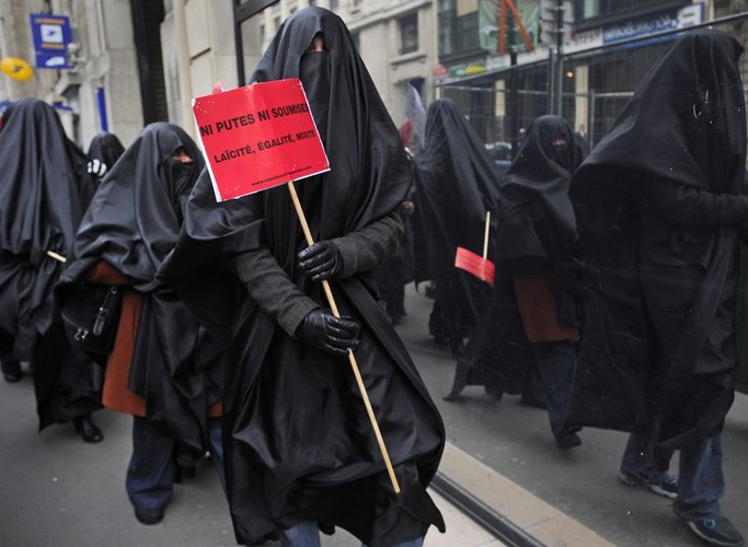 Przedstawicielki francuskiej organizacji 'Ani dziwki, ani uległe' ubrane w burki idą w stronę siedziby prawicowej partii UMP