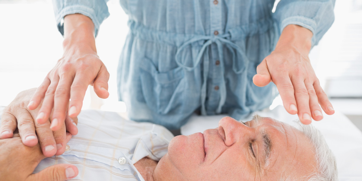 Man having Reiki treatment by therapist