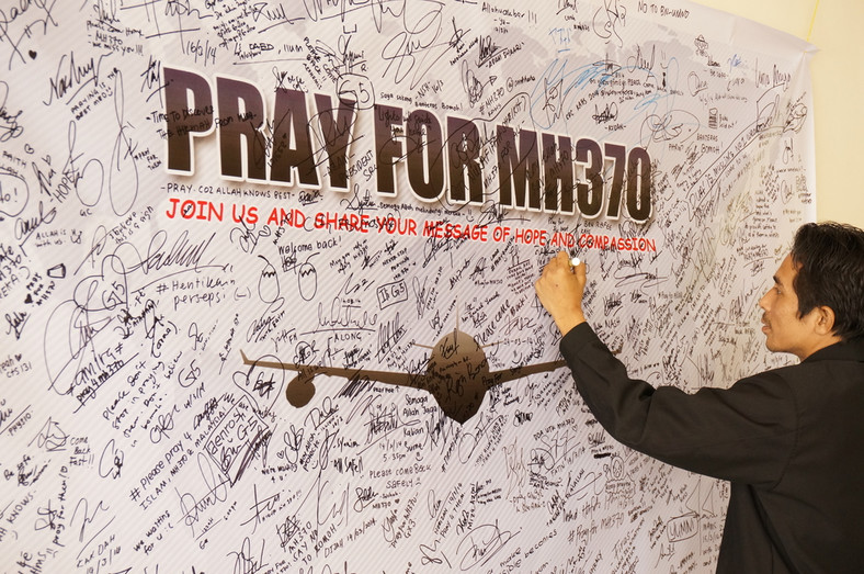 Mężczyzna pisze wiadomości i modli się za pasażerów zaginionego samolotu, 19 marca 2014 r.