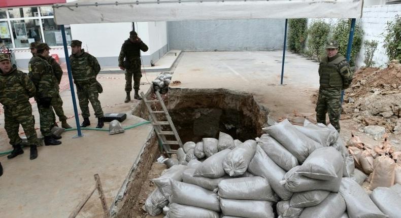 Military personnel of the Hellenic Army Explosive Ordnance Disposal (EOD) team stand at the site of a World War II bomb in Kordelio, a suburb of Thessaloniki, on February 12, 2017, ahead of an operation to defuse the bomb