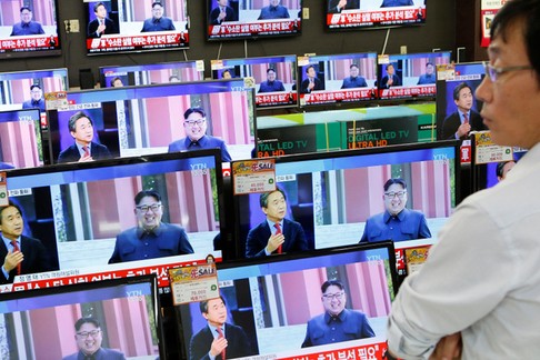 A sales assistant watches TV sets broadcasting a news report on North Korea's fifth nuclear test, in