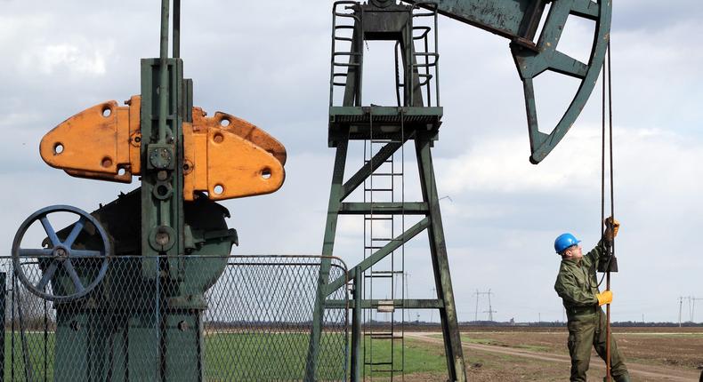 An oil worker checks a pump jack