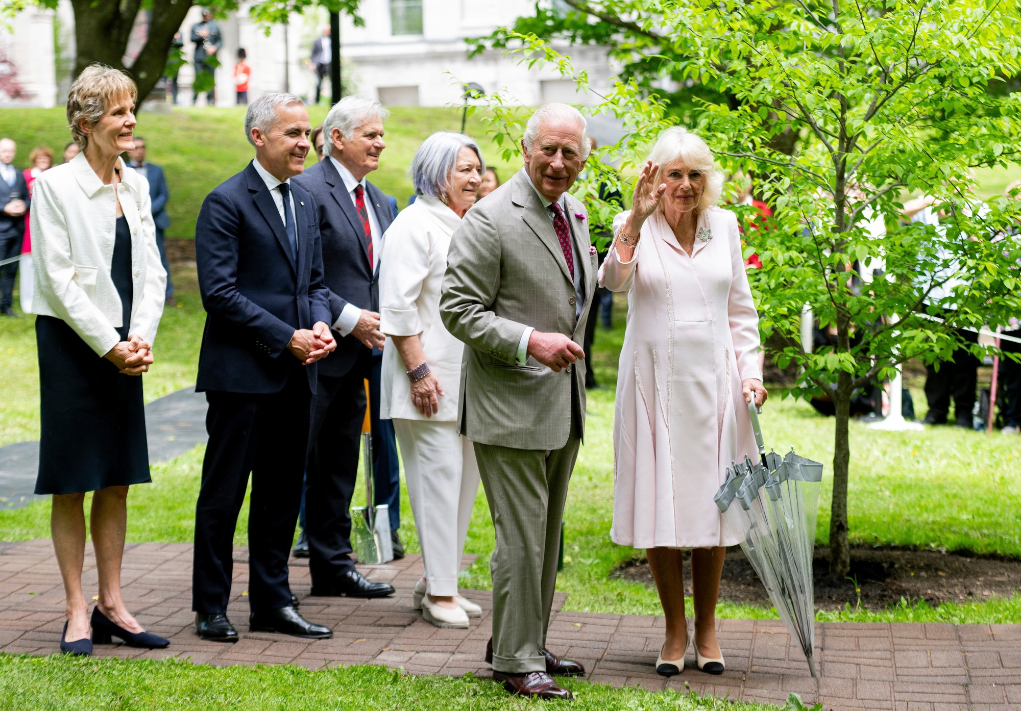 Kráľ Karol a kráľovná Kamila, vpredu, prichádzajú spolu s premiérom Markom Carneym, vzadu druhý zľava, generálnou guvernérkou Mary Simonovou, vzadu vpravo, Whitom Frasierom a Dianou Fox Carney pred ceremóniou sadenia stromu v Rideau Hall v Ottave.