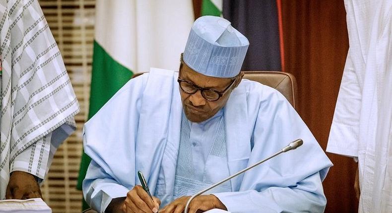 President Muhammadu Buhari signing (Premium Times)