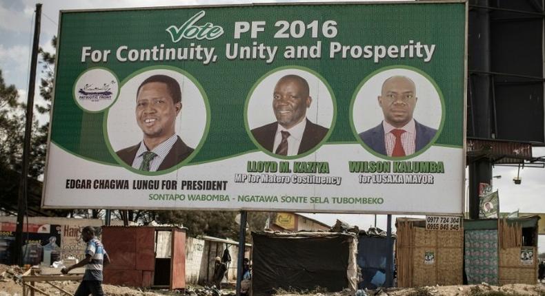 People walk by a billboard with picture of the incumbent president Edgar Lungu, of the Patriotic Front ruling Party, two days ahead of Zambian Presidential and legislative elections on August 9, 2016 