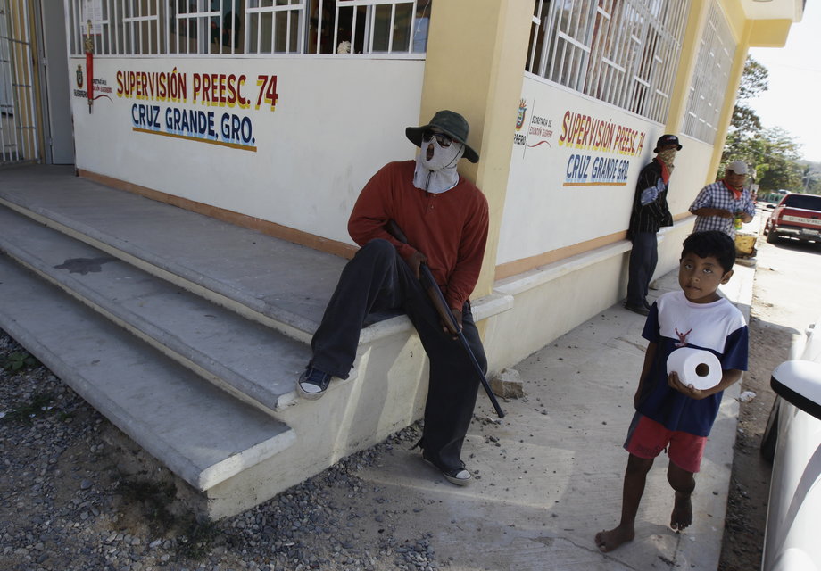 A boy walks past members of the "community Police," run by local residents to police their communities, as they stand guard in the town of Cruz Grande, in the Costa Chica region of the southern state of Guerrero, January 30, 2013.