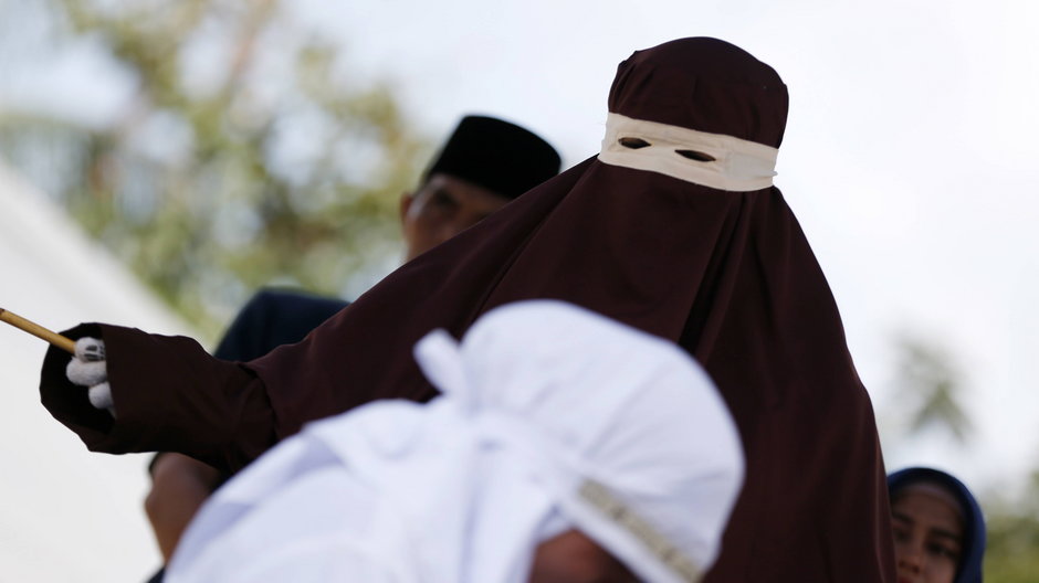 Funkcjonariuszka policji szariatu wymierza chłostę kobiecie w Aceh w Indonezji. Aceh jest jedynym regionem Indonezji, gdzie obowiązuje prawo szariatu.