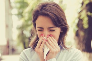 Woman with allergy symptoms blowing nose