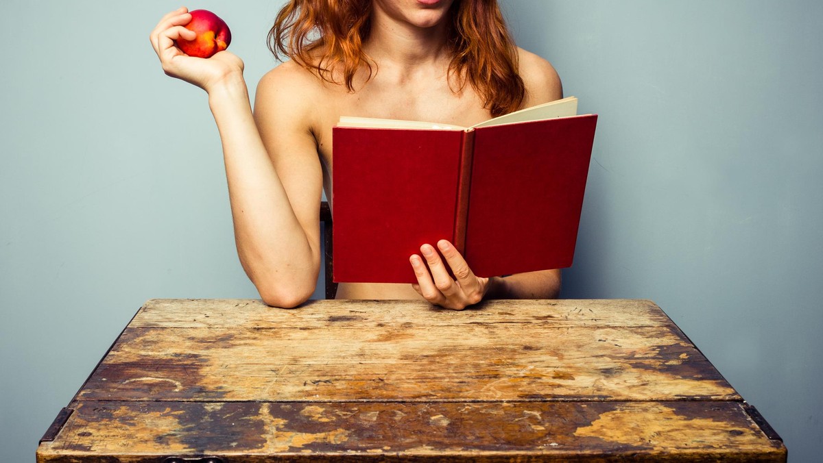 Naked woman reading and eating a peach