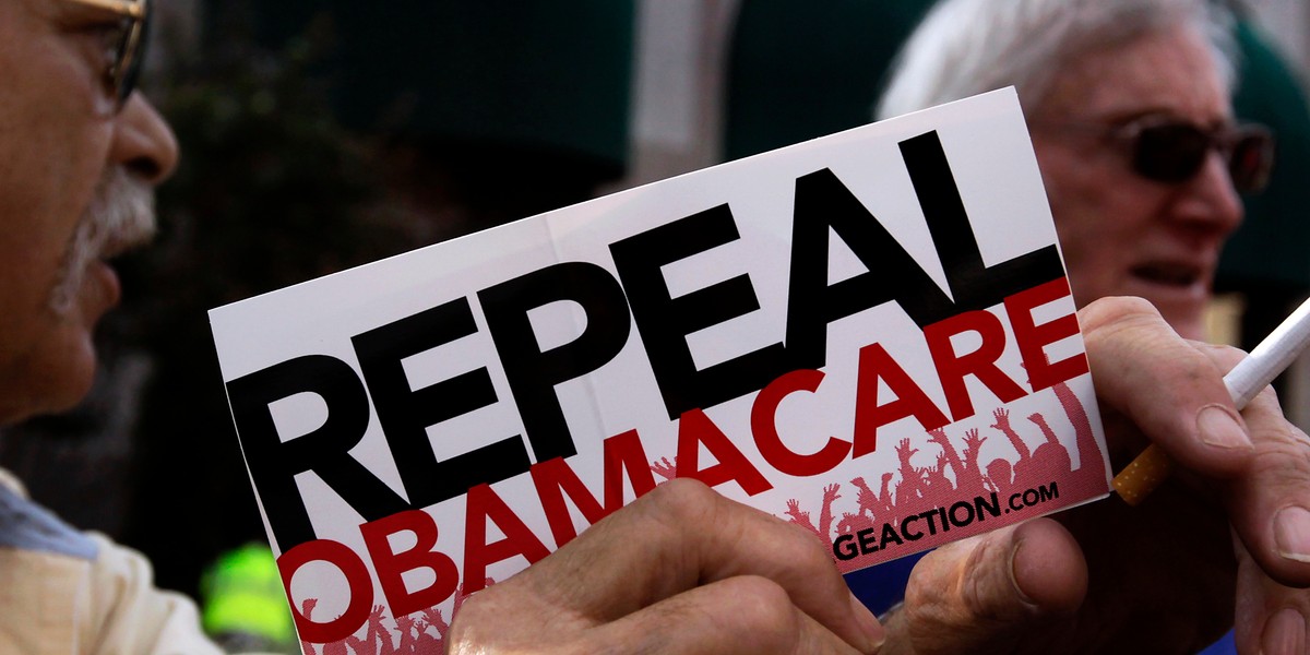 A small group of demonstrators stand outside of the HIlton Hotel and Suites prior to former South Carolina Senator Jim DeMint, president of the The Heritage Foundation, speaking at a "Defund Obamacare Tour" rally in Indianapolis August 26, 2013.