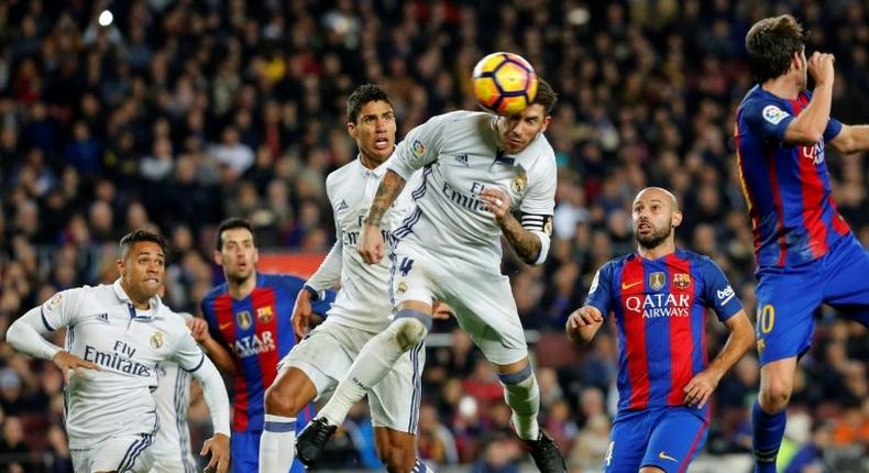 Real Madrid's defender Sergio Ramos (C) heads a ball to score the equalizer past Real Madrid's Raphael Varane (3rdL) and Barcelona's defender Javier Mascherano (R) during the Spanish league football match on December 3, 2016