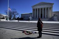 Flowers are seen as a woman stands in front of the Supreme Court building in Washington D.C. after t