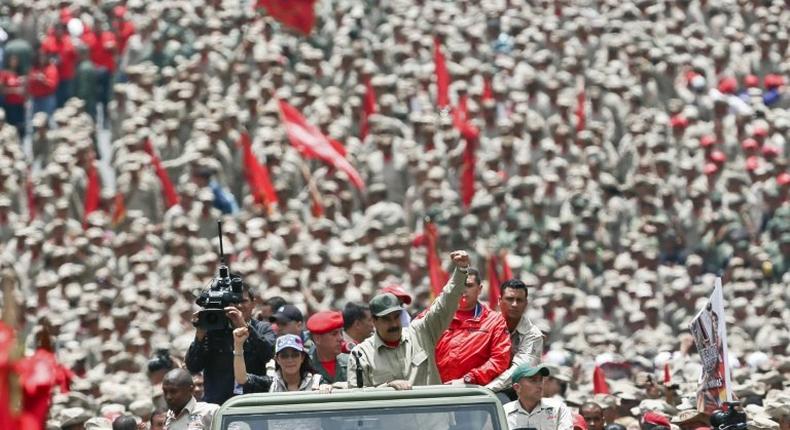 Venezuelan President Nicolas Maduro (C) saluting next to his wife Cilia Flores as they arrive for the celebrations for the seventh anniversary of the Bolivarian Militia in Caracas on April 17, 2017