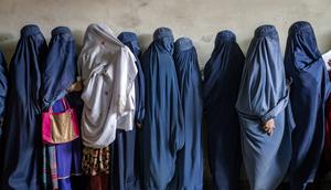 Afghan women wait to receive food rations distributed by a humanitarian aid group in Kabul on May 23, 2023.