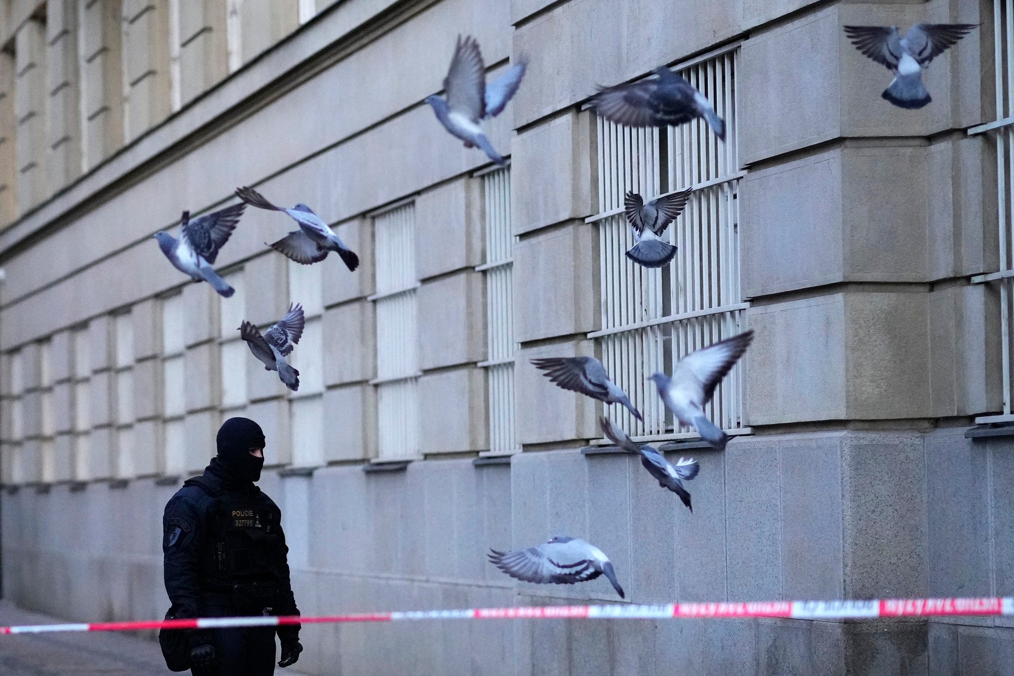 Policajt hliadkuje pred budovou Filozofickej fakulty Univerzity Karlovej po streľbe v centre Prahy.