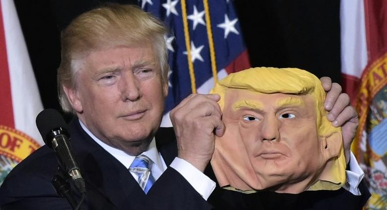 Republican presidential nominee Donald Trump holds a mask of himself wduring a campaign rally in Sarasota, Florida, on November 7, 2016