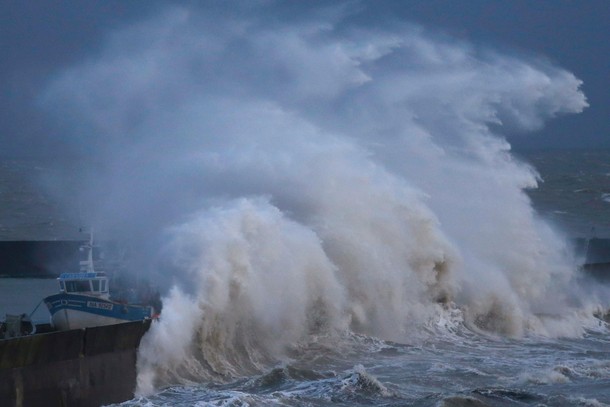 A high wave crashes on the protecting wall at the fishing harbour in Pornic, France as stormy weathe