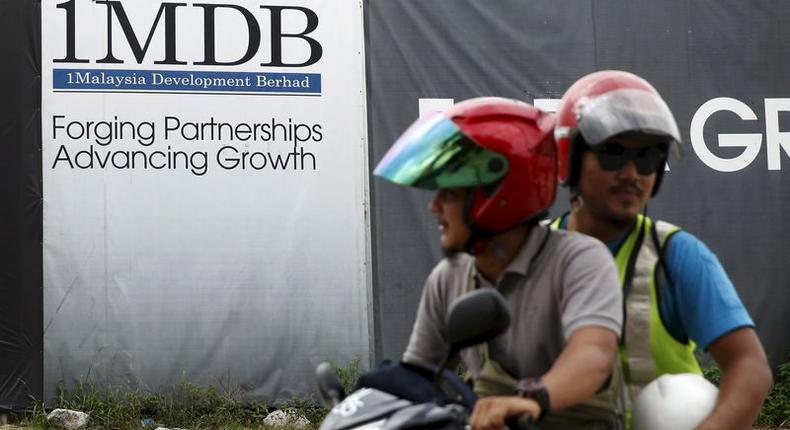 Motorcyclists pass a 1Malaysia Development Berhad (1MDB) billboard at the Tun Razak Exchange development in Kuala Lumpur, Malaysia, February 3, 2016. REUTERS/Olivia Harris/File Photo