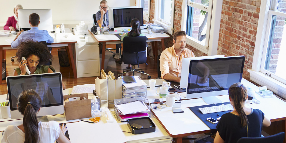 Wide Angle View Of Busy Design Office With Workers At Desks