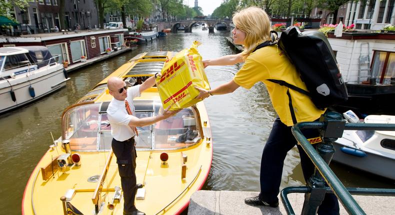 A DHL manager hands a package to a courier from a boat carrying express packages in one of the canals of Amsterdam.REUTERS/Robin van Lonkhuijsen/United Photos