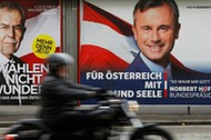 A motorcyclist passes presidential election campaign posters of Van der Bellen and Hofer in Vienna