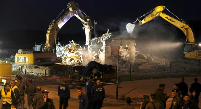 Diggers under the supervision of Israeli forces destroy a house in the Jewish settlement of Ofra in the occupied West Bank, on February 28, 2017