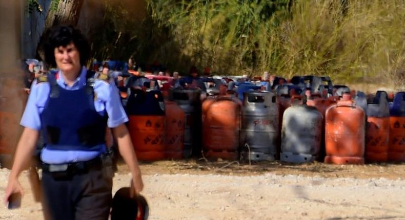 A policewoman walks with dozen of gas bottles in the background in Alcanar, during a search linked to the Barcelona and Cambrils attacks