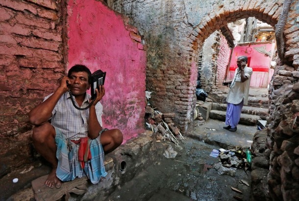 Labourers speak on wireless phones in an alley outside a local telephone booth in Kolkata