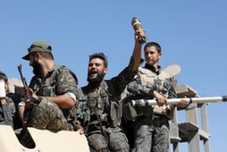 Fighters of Syrian Democratic Forces jubilate aboard an armoured fighting vehicle after Raqqa was liberated from the Islamic State militants, in Raqqa