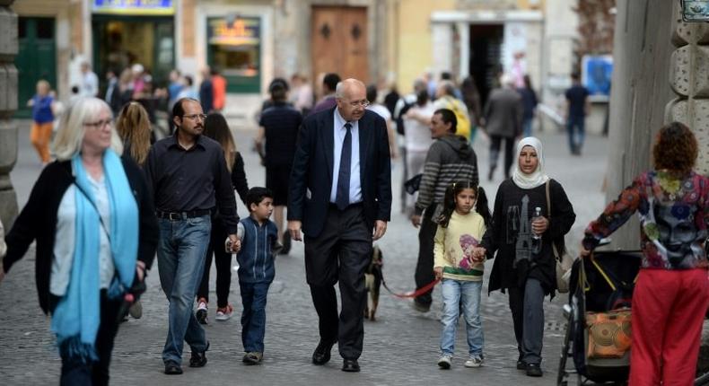 A family of Syrian refugees part of the 12 Syrian asylum seekers Pope Francis brought back with him from Greek island Lesbos, walk with a member of the St. Egidio Roman Catholic Charity (C), on April 18, 2016 in a strret of Rome