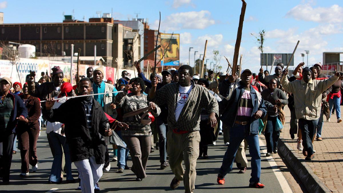Striking public servants run through the streets outside the Chris Hani Baragwanath Hospital in Soweto near Johannesburg, South Africa