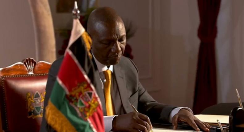 President William Ruto signs a document at State House