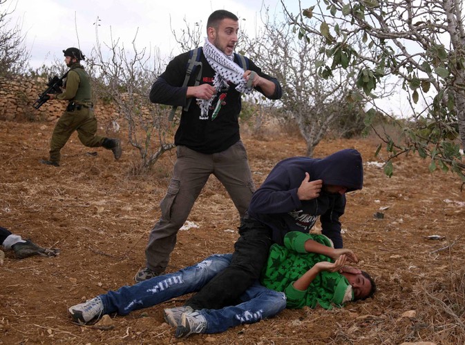 Izraelscy policjanci przebrani za Palestyńczyków chwytają palestyńskiego demonstranta, który sprzeciwia się budowie żydowskich osiedli