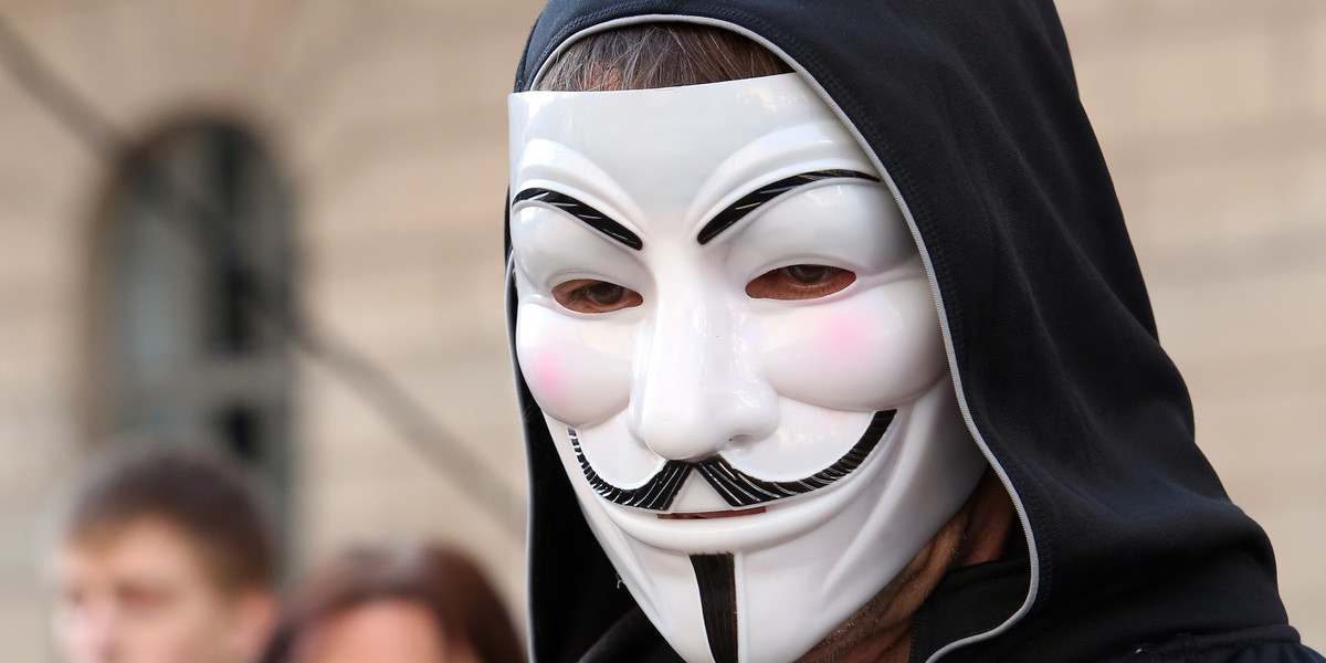 A demonstrator wearing a Guy Fawkes mask uses a mobile phone.