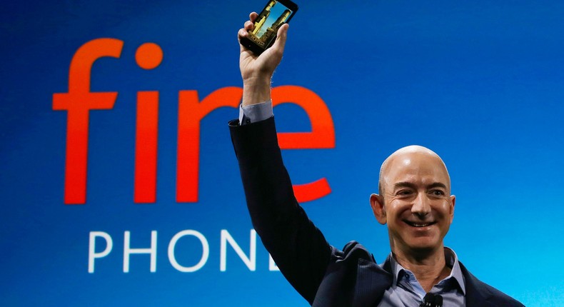 Jeff Bezos holds up an Amazon Fire phone in 2014, a product that he would later call a failure four years later. Now, the company may be revisiting the cell phone space, but only as a wireless provider partnered with another service.Ted S. Warren/AP