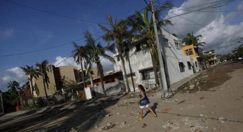 A woman walks along a street damaged by the heavy rains after the passing of Hurricane Patricia in Barra de Navidad, Mexico October 24, 2015.