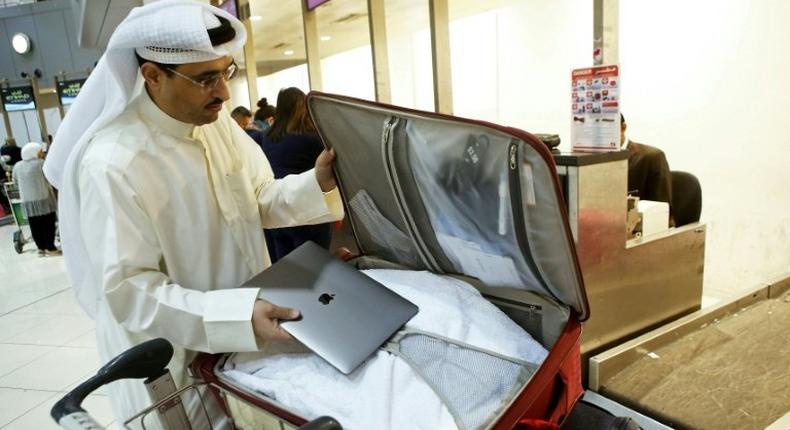 This file photo taken on March 23, 2017 shows Kuwaiti social media activist Thamer al-Dakheel Bourashed putting his laptop inside his suitcase at Kuwait International Airport in Kuwait City before boarding a flight to the United States