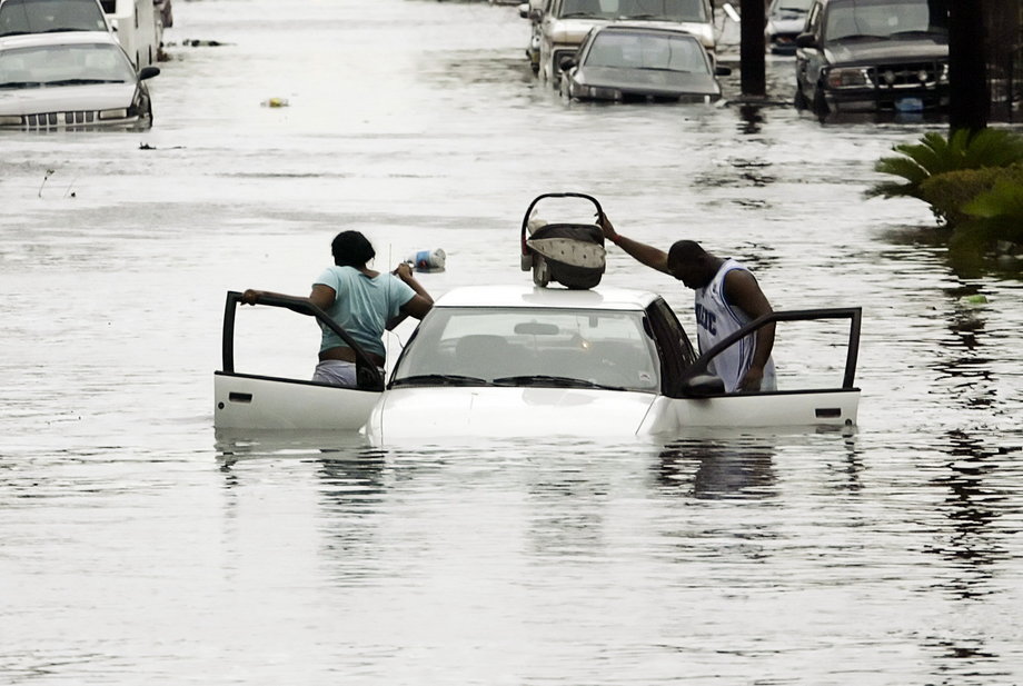 A man puts his baby on top of his car as he and a woman abandon their car after it started to float after Hurricane Katrina hit the Treme area of New Orleans August 29, 2005.