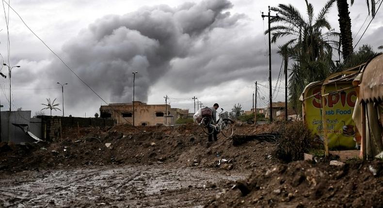 An Iraqi carries a bicycle in West Mosul during the offensive to retake the city from Islamic State group, on March 16, 2017