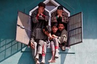 People react as they sit in a window of a mosque during the funeral of Tauseef Ahmad Wagay, a suspec