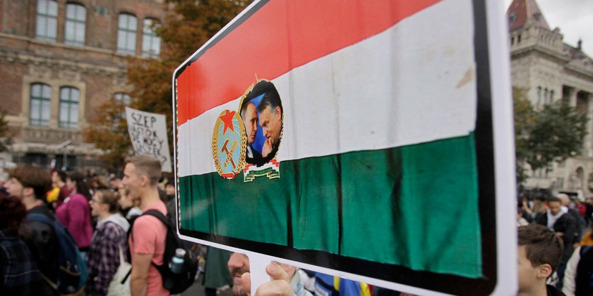 Zdjęcie ilustracyjne. Mężczyzna trzyma sztandar z węgierską flagą i zdjęciem prezydenta Rosji Władimira Putina z premierem Węgier Viktorem Orbanem podczas protestu nauczycieli i uczniów przeciwko polityce edukacyjnej rządu, 23 października 2022 r., Budapeszt, Węgry. 