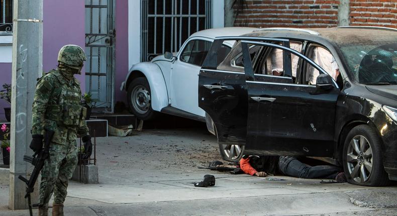 A Mexican marine looks at the body of a gunman as it lies next to a vehicle after a gun fight in Culiacan, in Sinaloa state, Mexico, February 7, 2017.