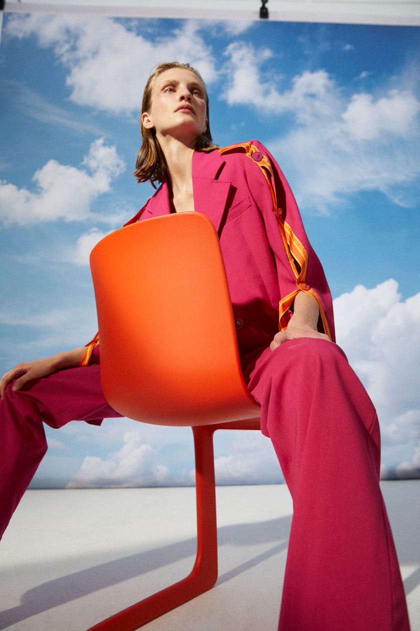 VERSACE Gerade geschnittener Hosenanzug aus Schurwolle mit Ziernähten.  VITRA Stuhl Evo-C aus recycelbarem Kunststoff im Farbton Poppy Red.