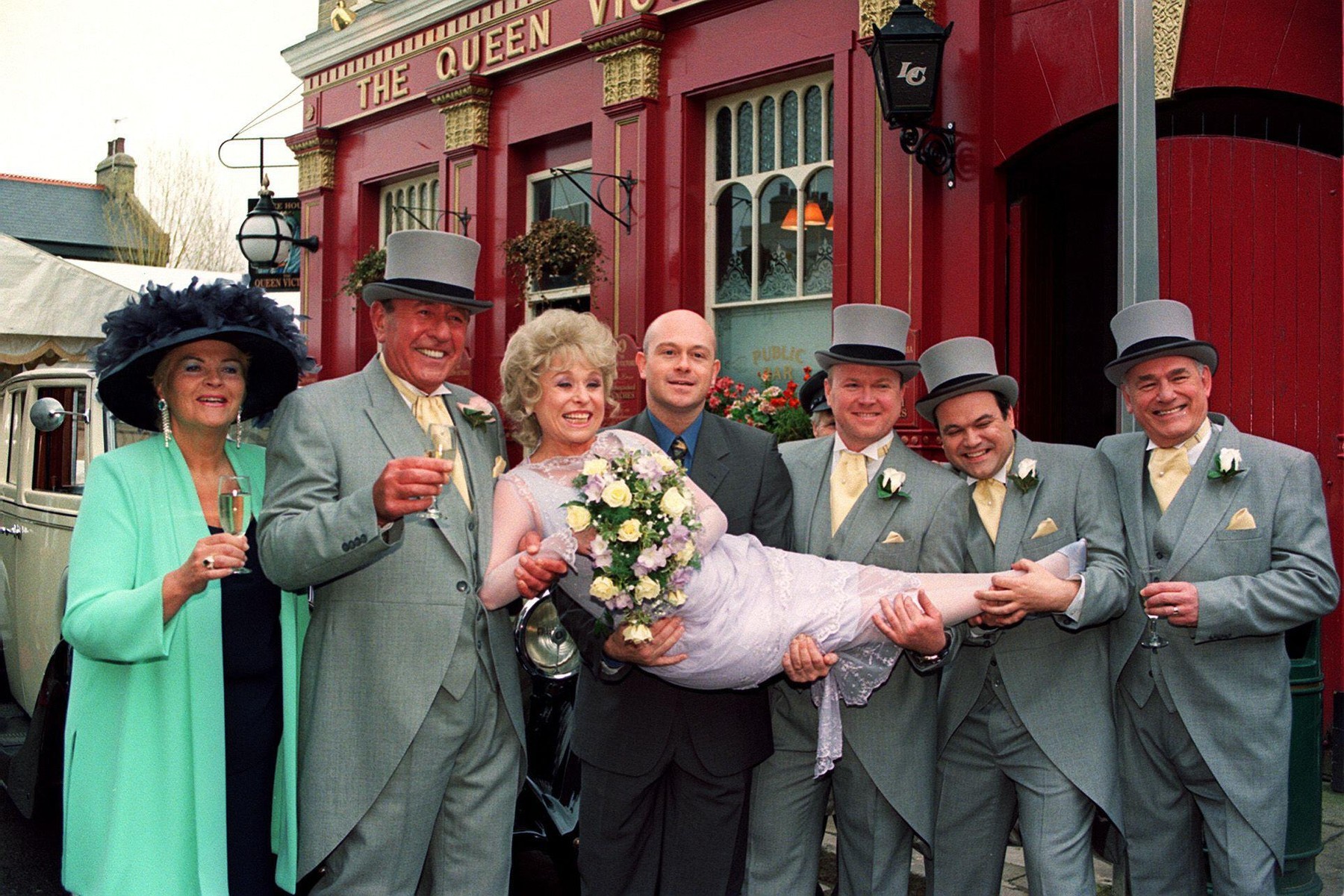 Zľava Pam St Clement, Mike Reid, Barbara Windsor, Ross Kemp, Steve McFadden, Shaun Williamson a Tony Caunter pred pubom Queen Vic v štúdiách Elstree. 